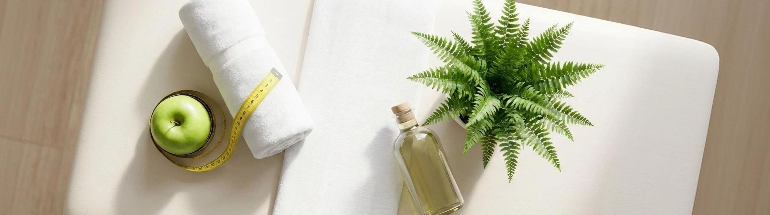 Toalla con cinta métrica, manzana verde, frasco de aceite y planta decorativa. Servicios