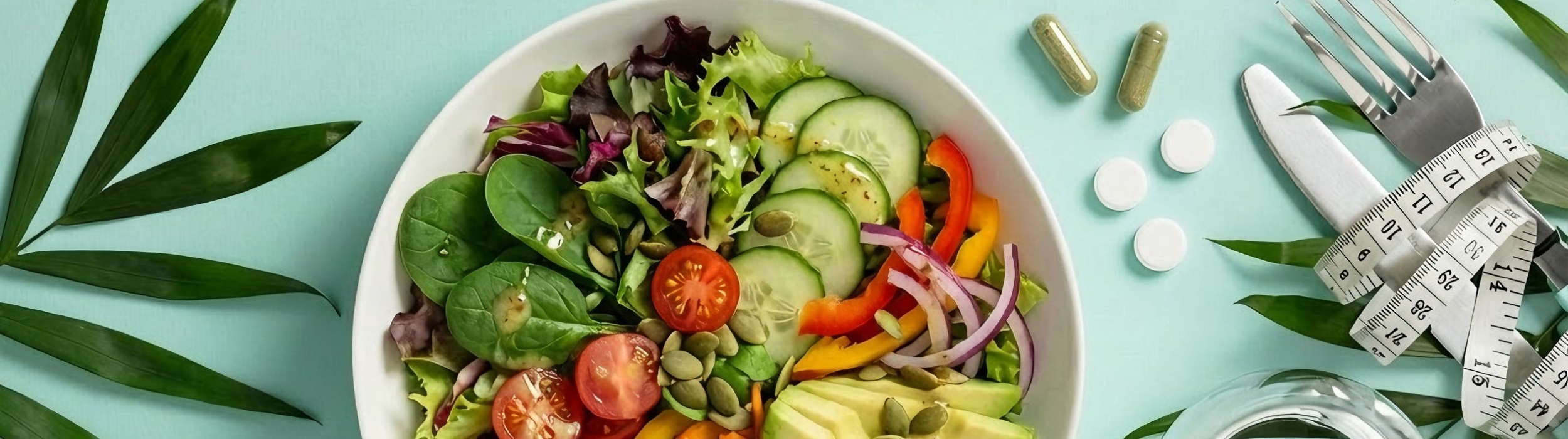 Ensalada colorida con suplementos, cinta métrica y vaso de agua. Control de peso