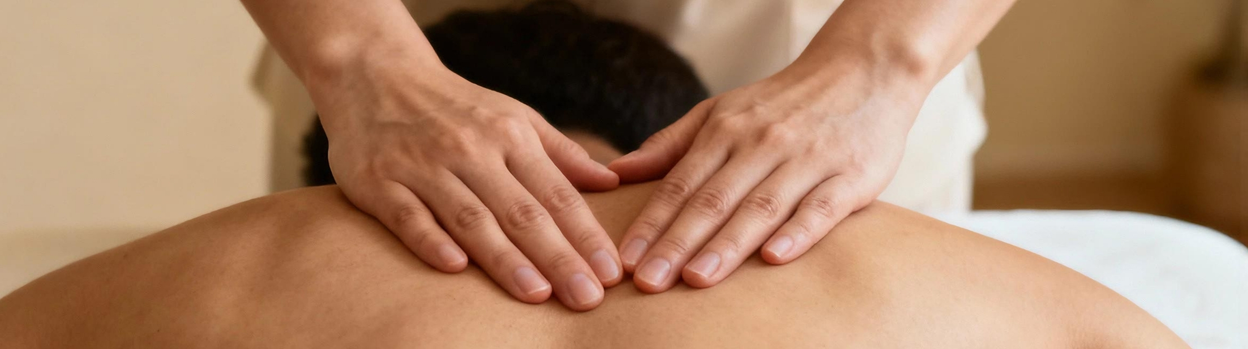 Manos aplicando masaje en la espalda de una persona tumbada. Quiromasaje